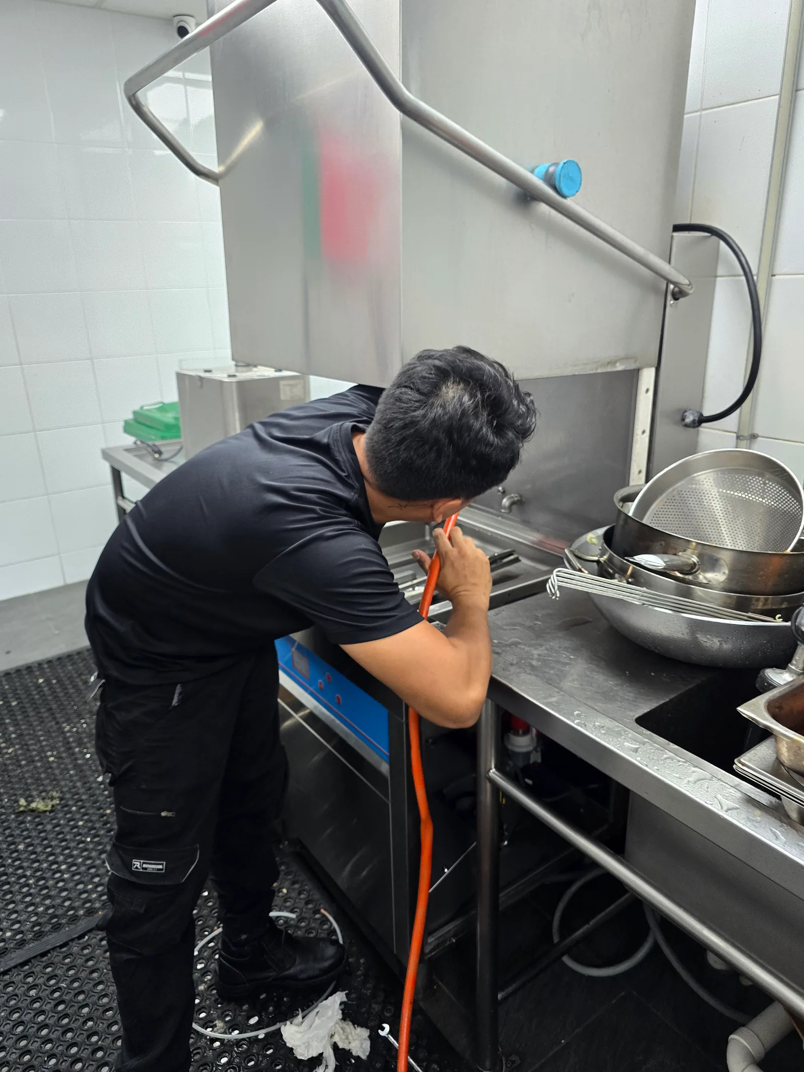 An EHS technician performing routine maintenance on a commercial dishwasher.